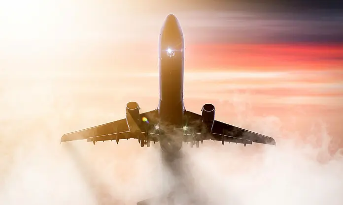 Flugzeug steigt durch Wolken im Sonnenaufgang
