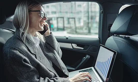Beraterin telefoniert im Auto und arbeitet am Laptop – mobile Dokumentation und Aufzeichnung im Finanzumfeld
