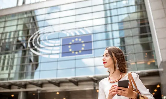 Woman with a smartphone in front of the EU Parliament – GDPR awareness and data protection