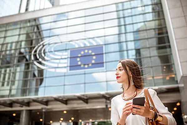 Woman with a smartphone in front of the EU Parliament – GDPR awareness and data protection