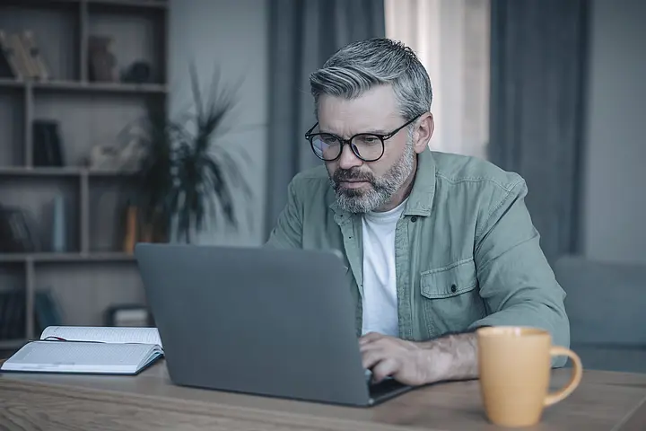 Person führt ein Beratungsgespräch zu Versicherungsleistungen über den Laptop; der Dienstleister arbeitet FCA-, MiFID- und Dodd-Frank-konform