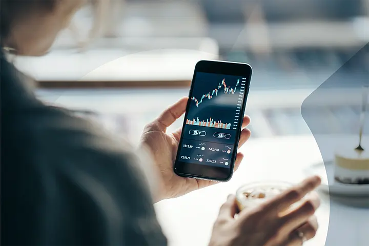 Person nutzt eine Trading-App auf dem Smartphone für den Kauf und Verkauf von Wertpapieren..