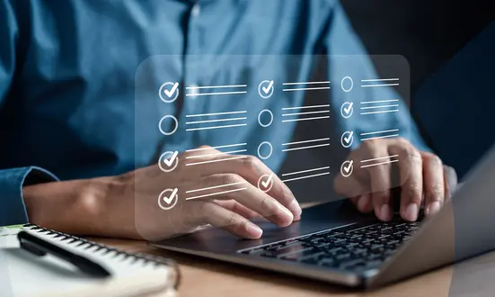 Hände am Laptop mit Checkliste zur Optimierung von Qualitätsmanagement-Prozessen