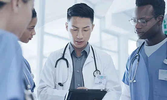 Doctor discusses with three carers in hospital.