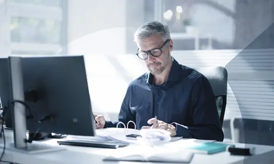 Man sits at his desk and checks financial documents in the office to ensure financial compliance.