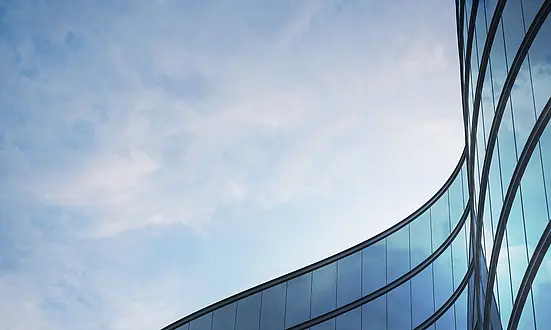 Geschwungene Glasfassade vor blauem Himmel