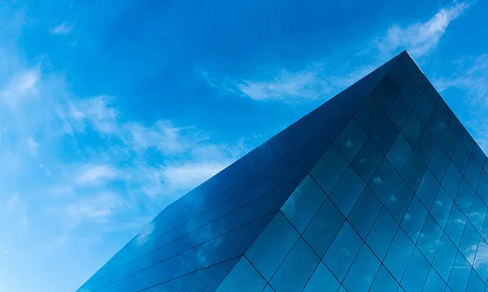 Modernes Glasgebäude mit blauem Himmel und Wolken